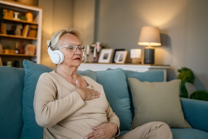 Senior-woman-sitting-on-couch-wearing-headphones-meditating