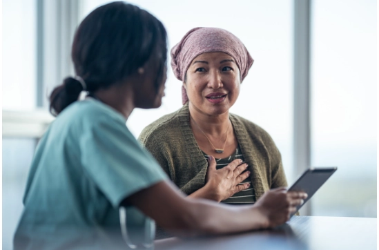 Woman-wearing-headscarf-talking-to-doctor-holding-a-tablet-device